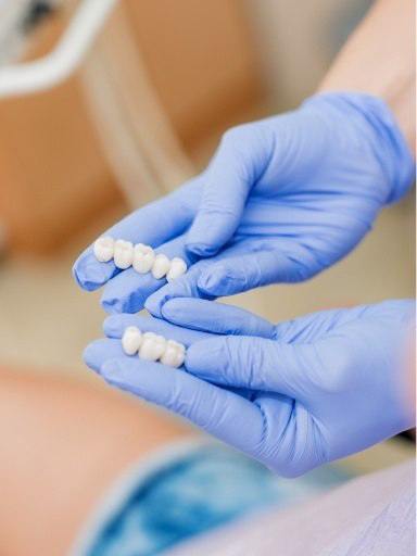 Gloved hands holding dental bridges