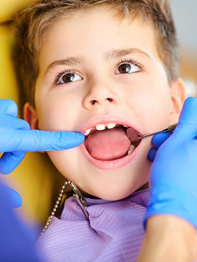Little boy in yellow dental chair having teeth examined