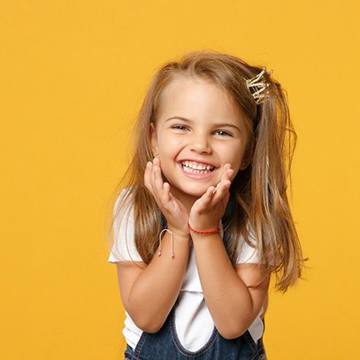 Happy, smiling little girl against yellow background