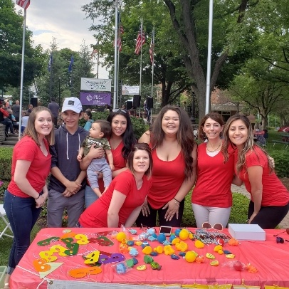 People in red shirts gathered around table and smiling