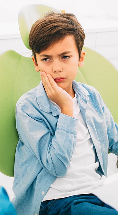 Little boy cringing in pain at dentist’s office