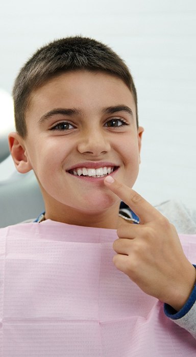 Young boy pointing at healthy tooth after pulp treatment